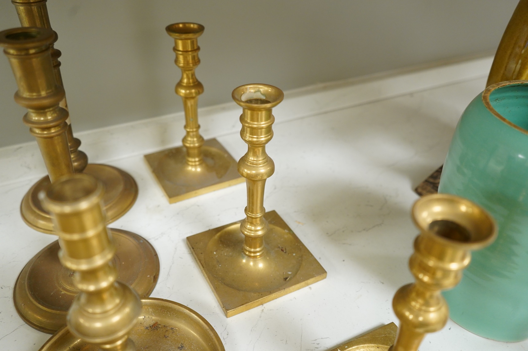 Two fire marks and a collection of brass candlesticks, tallest 25.5cm